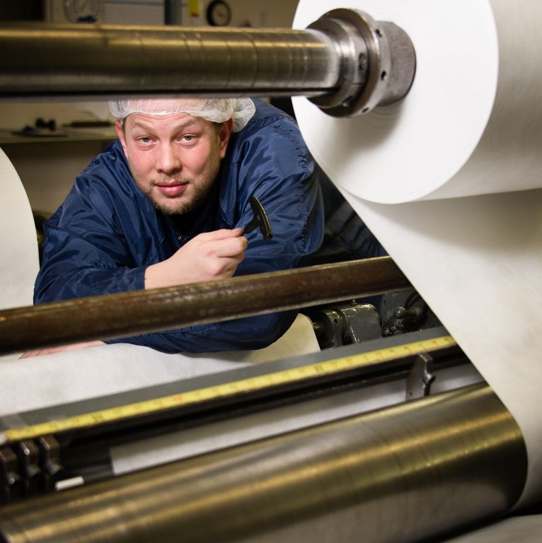 worker with paper press in factory